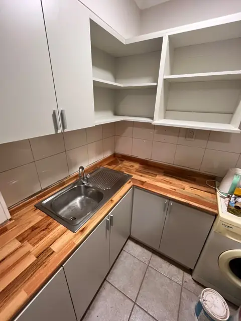 Detalle de cocina a medida con mesada de madera maciza, alacenas y estantes esquineros abiertos