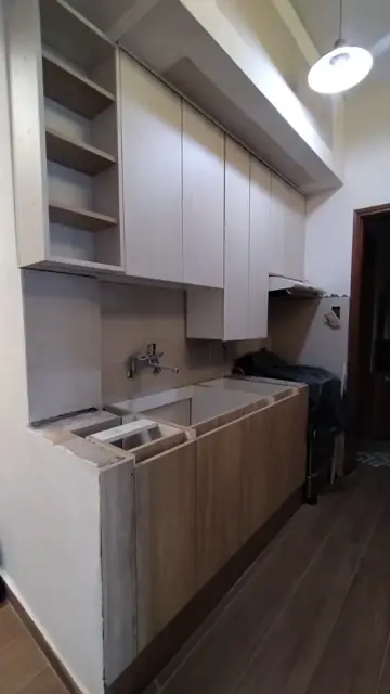 Cocina a medida en instalación: alacenas hasta el techo y bajo mesadas en melamina símil madera