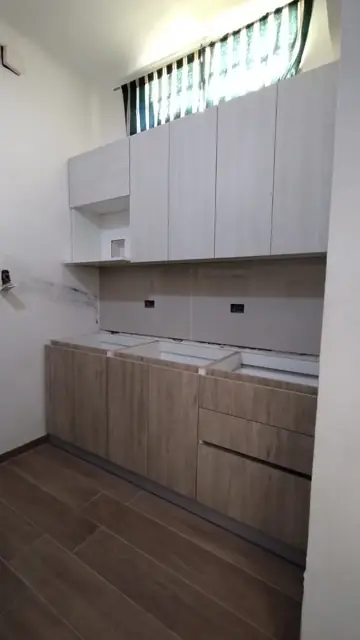 Cocina a medida en instalación con cajonera, bajo mesadas símil madera y alacenas claras