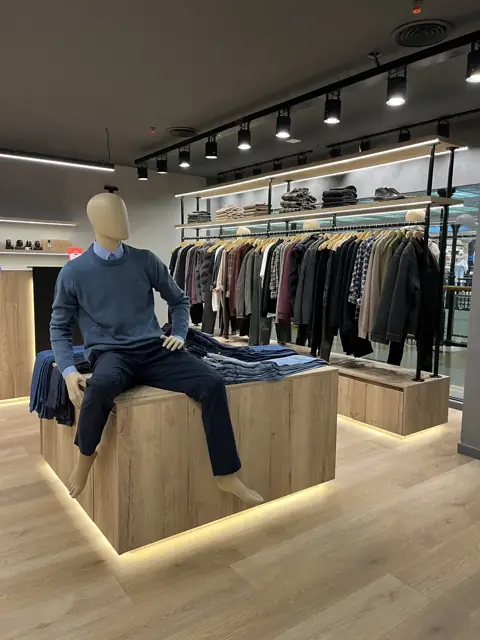 Equipamiento comercial a medida para local de ropa en shopping de Córdoba: islas exhibidoras de madera con LED