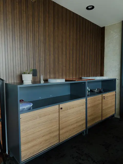 Muebles de guardado a medida con frentes símil madera y estructura gris para oficinas