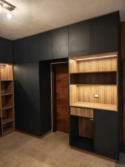 Placard negro de piso a techo con biblioteca iluminada en madera, a medida para playroom