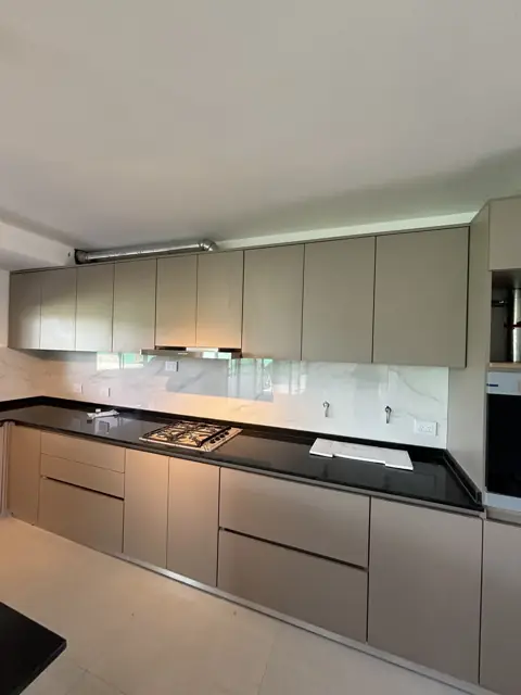 Cocina a medida con alacenas y bajo mesadas en melamina gris claro y mesada negra, Córdoba